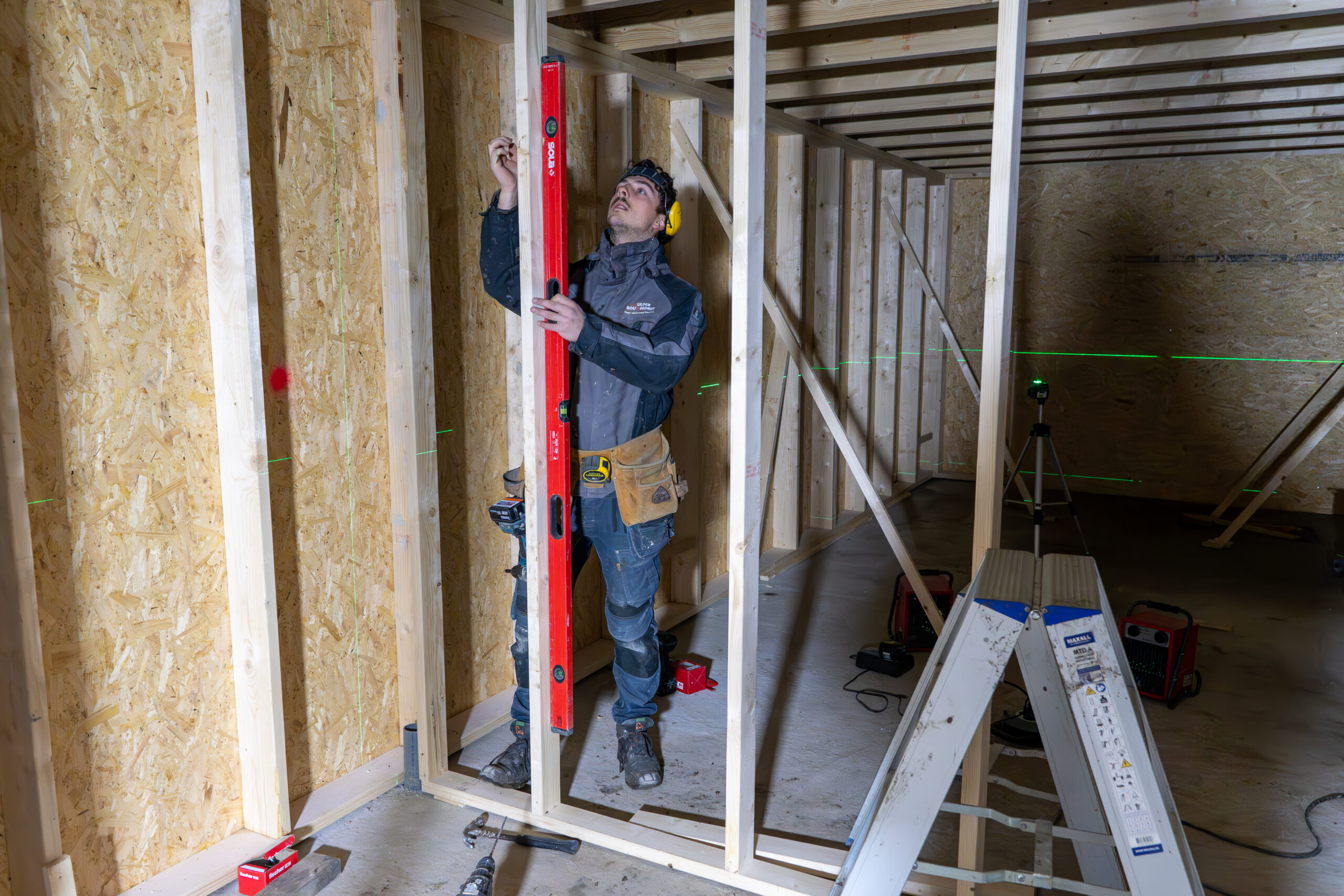 Bouwvakker meet houten muur met waterpas - Mulder Bouwbedrijf (Eelde)